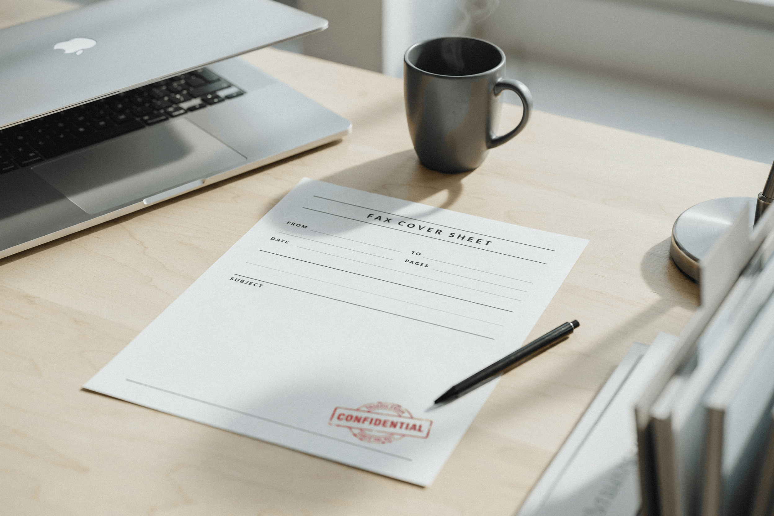 blank fax cover sheet on a desk beside a laptop, ready to fill in and fax online